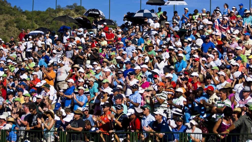 A crowd gather in a grandstand to watch golf