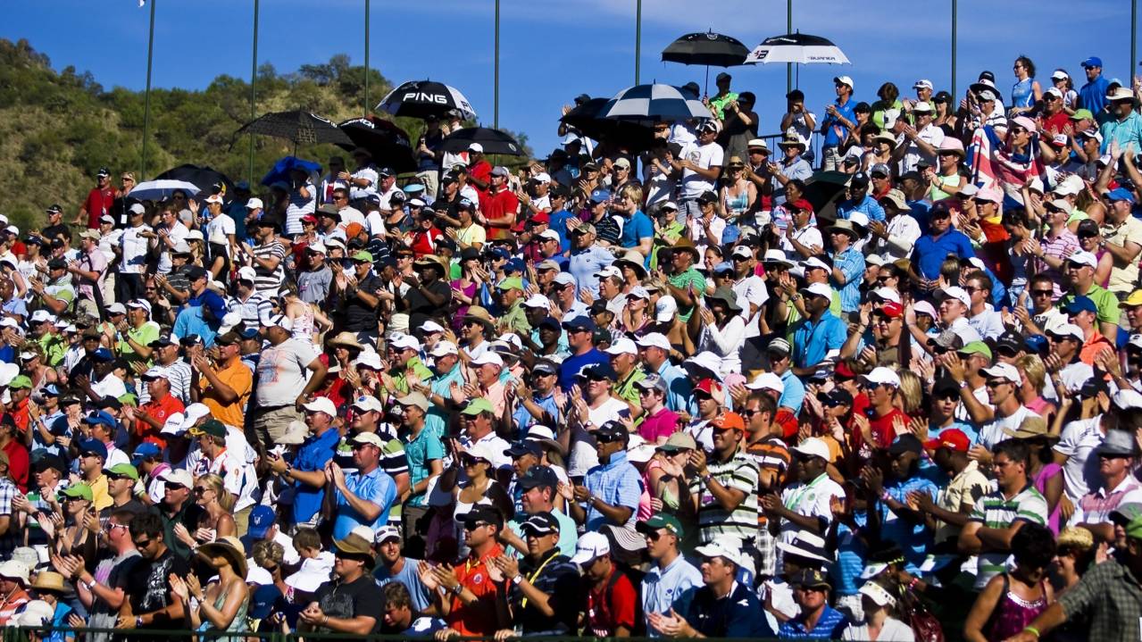 A crowd gather in a grandstand to watch golf