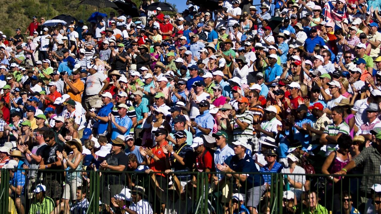 A crowd gather in a grandstand to watch golf