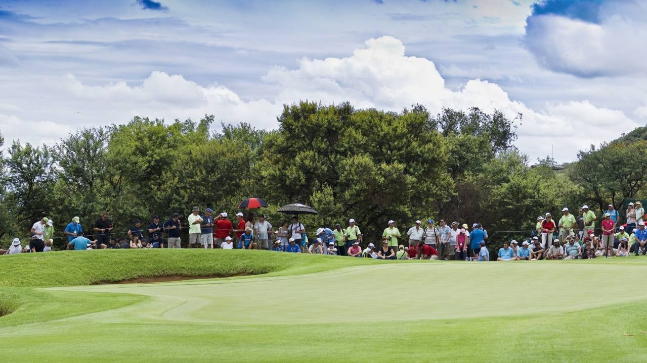 A crowd gathered around a golf green