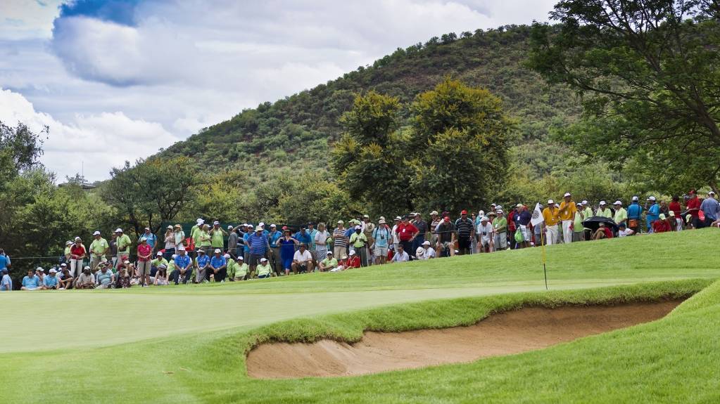 A gallery gathered around a golf green featuring a bunker