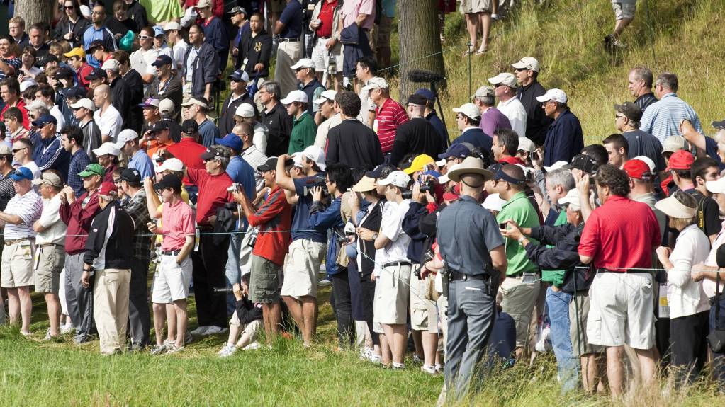 A gallery gathers behind the ropes to watch a golf event