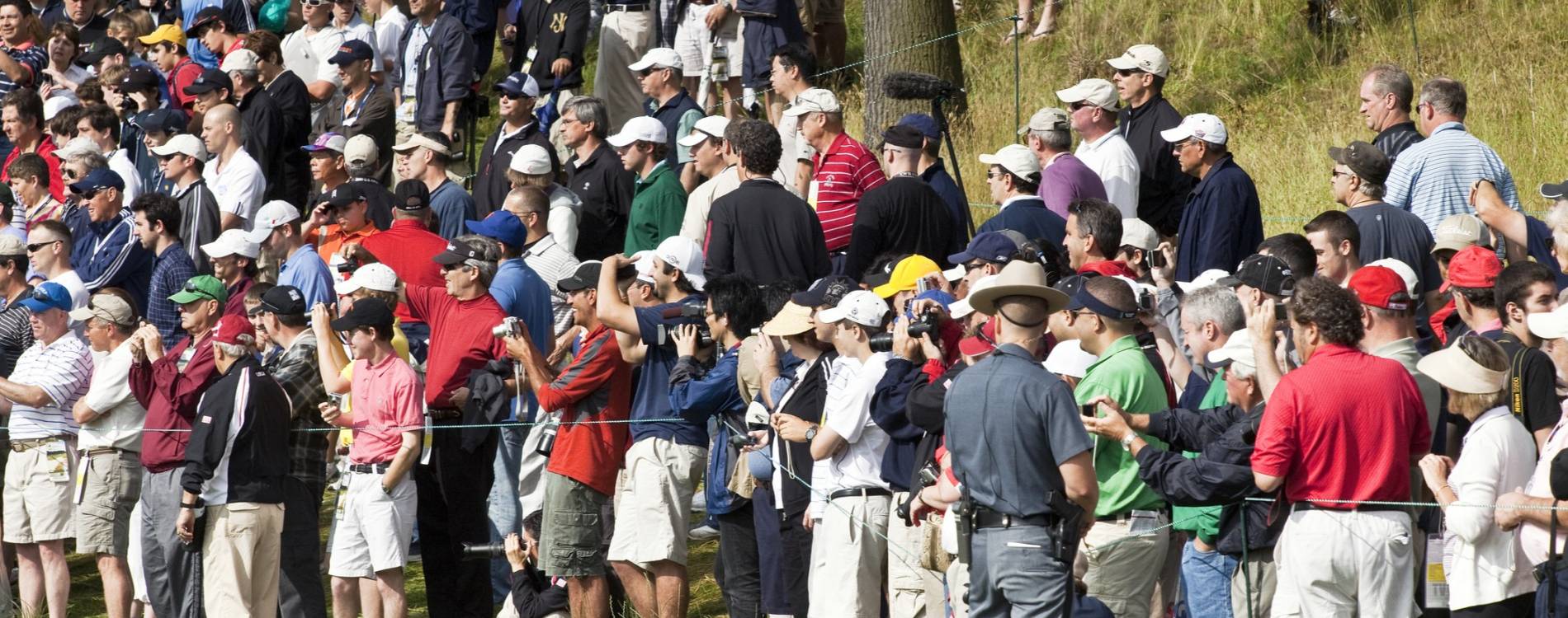 A gallery gathers behind the ropes to watch a golf event