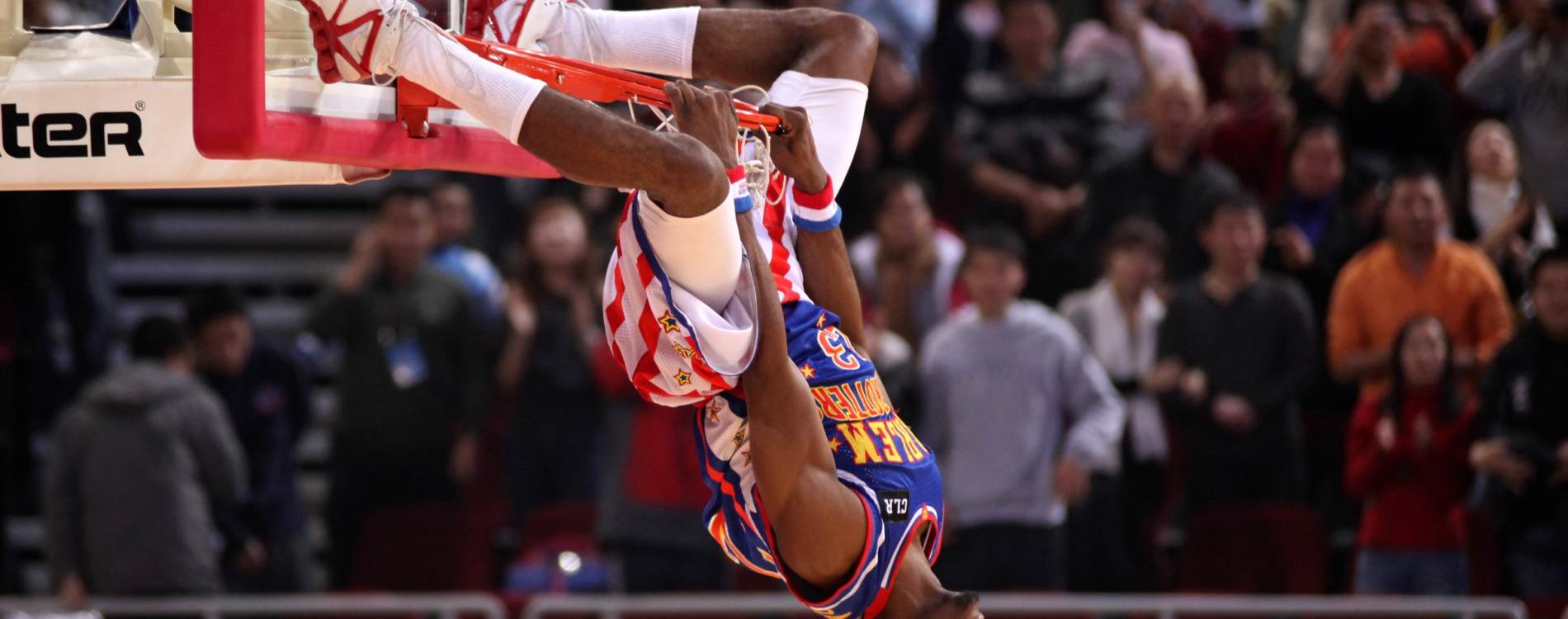 A Harlem Globetrotters player hangs off the hoop