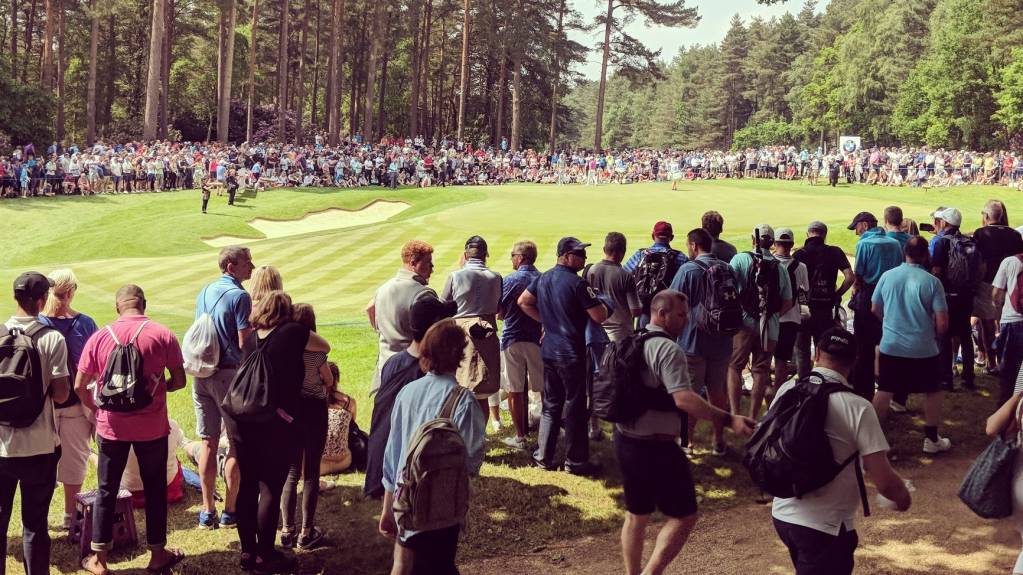 A large crowd gathers around the green at the BMW PGA Championship