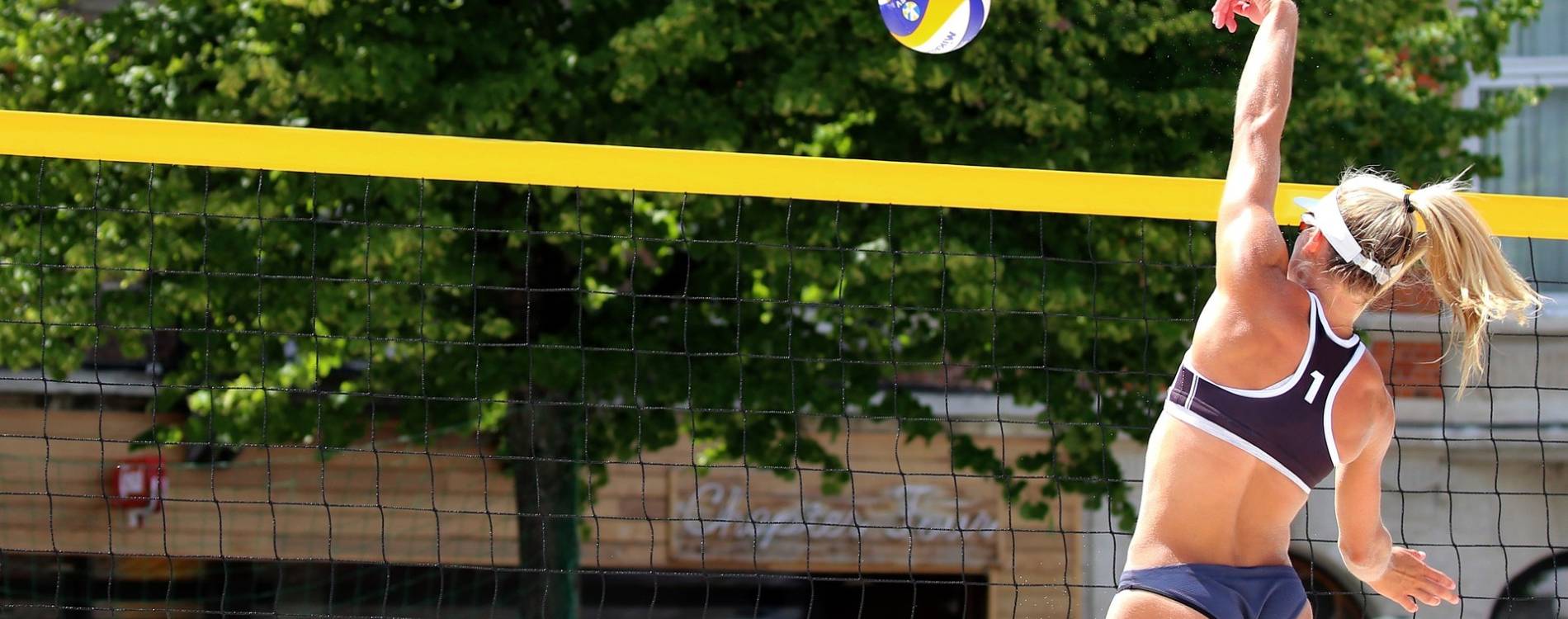 Beach volleyball player tips ball over the net