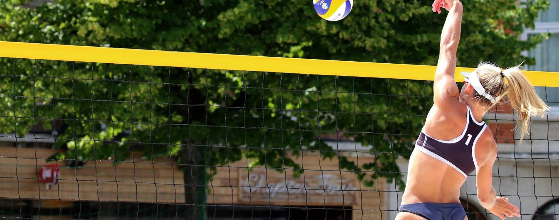 Beach volleyball player tips ball over the net
