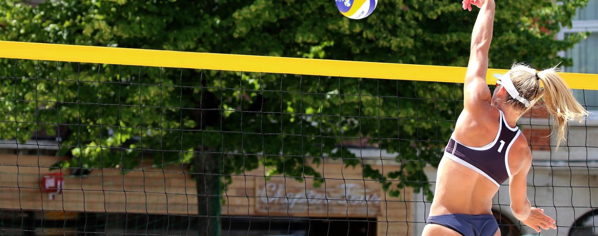 Beach volleyball player tips ball over the net