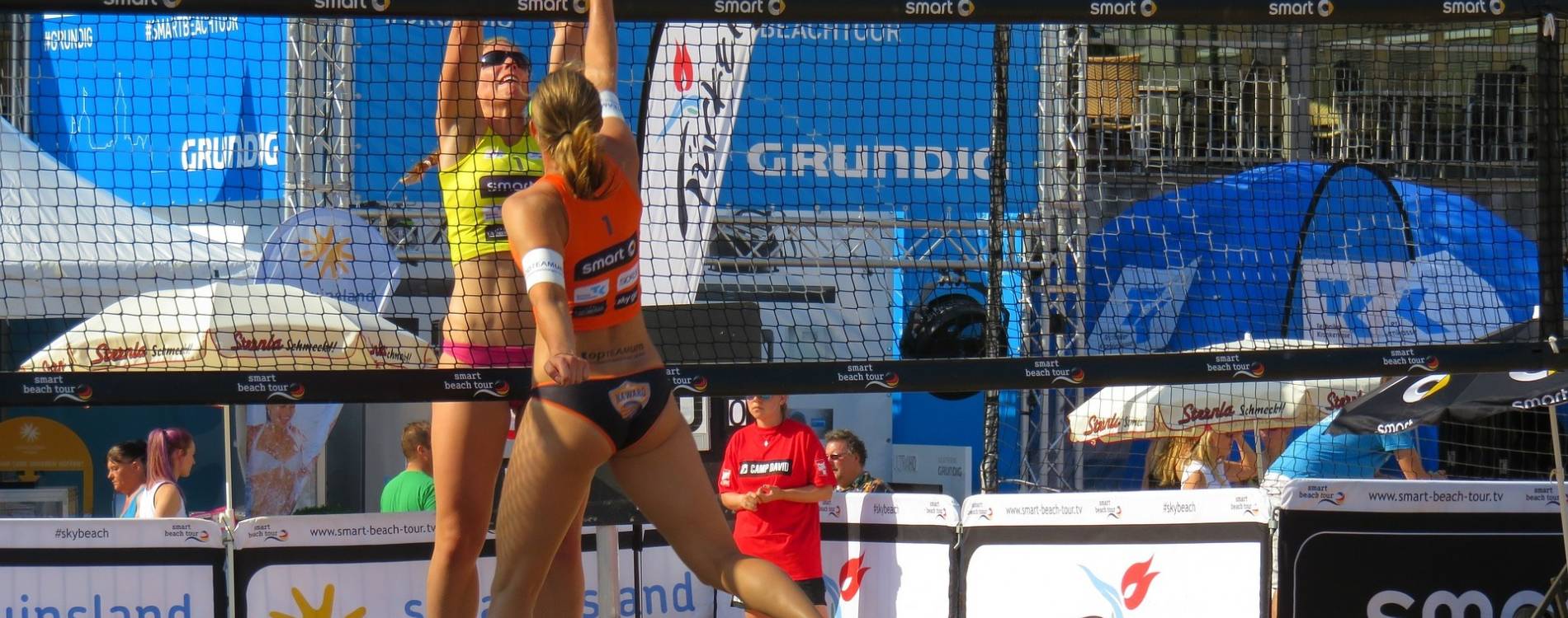 Beach volleyball players jump for the ball