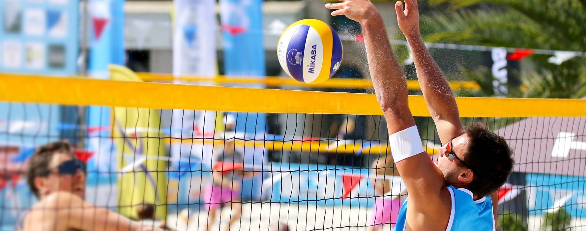 Beach volleyball players pushing ball over net