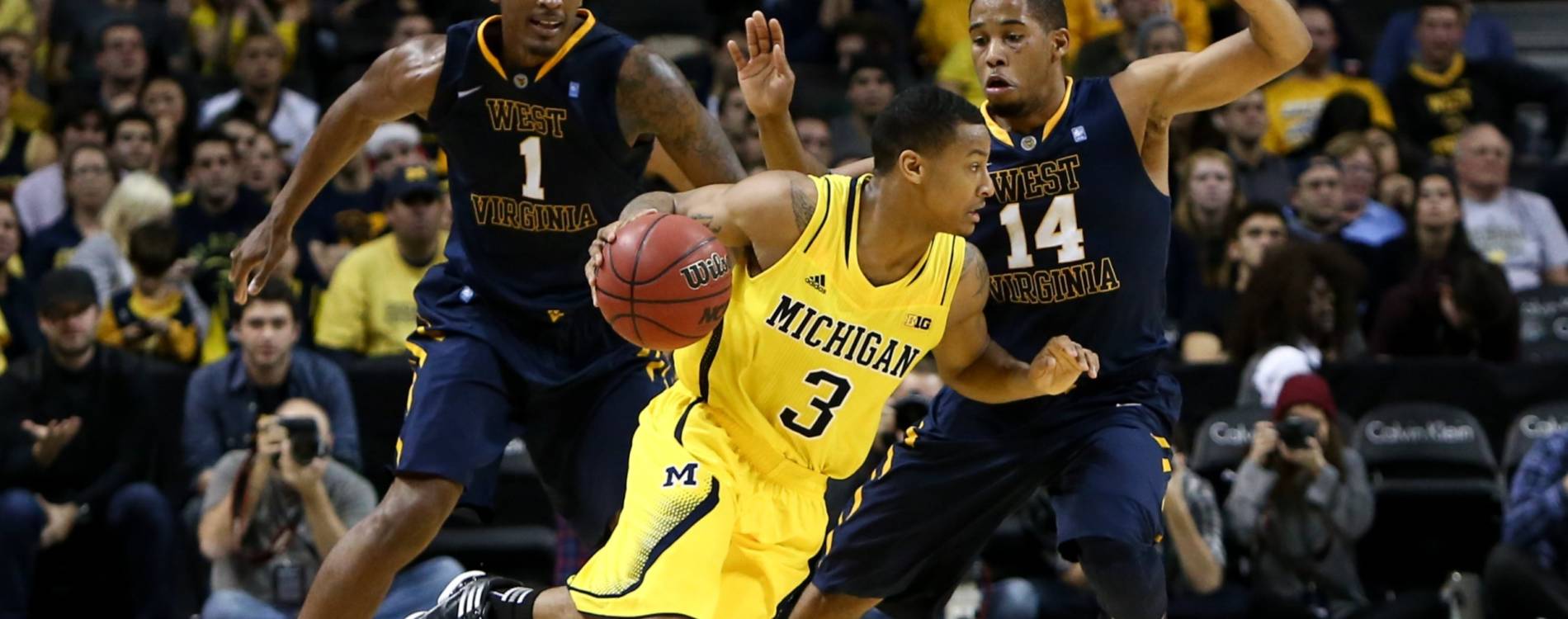 Michigan Wolverines' Trey Burke dribbles past West Virginia Mountaineers' Dominique Rutledge