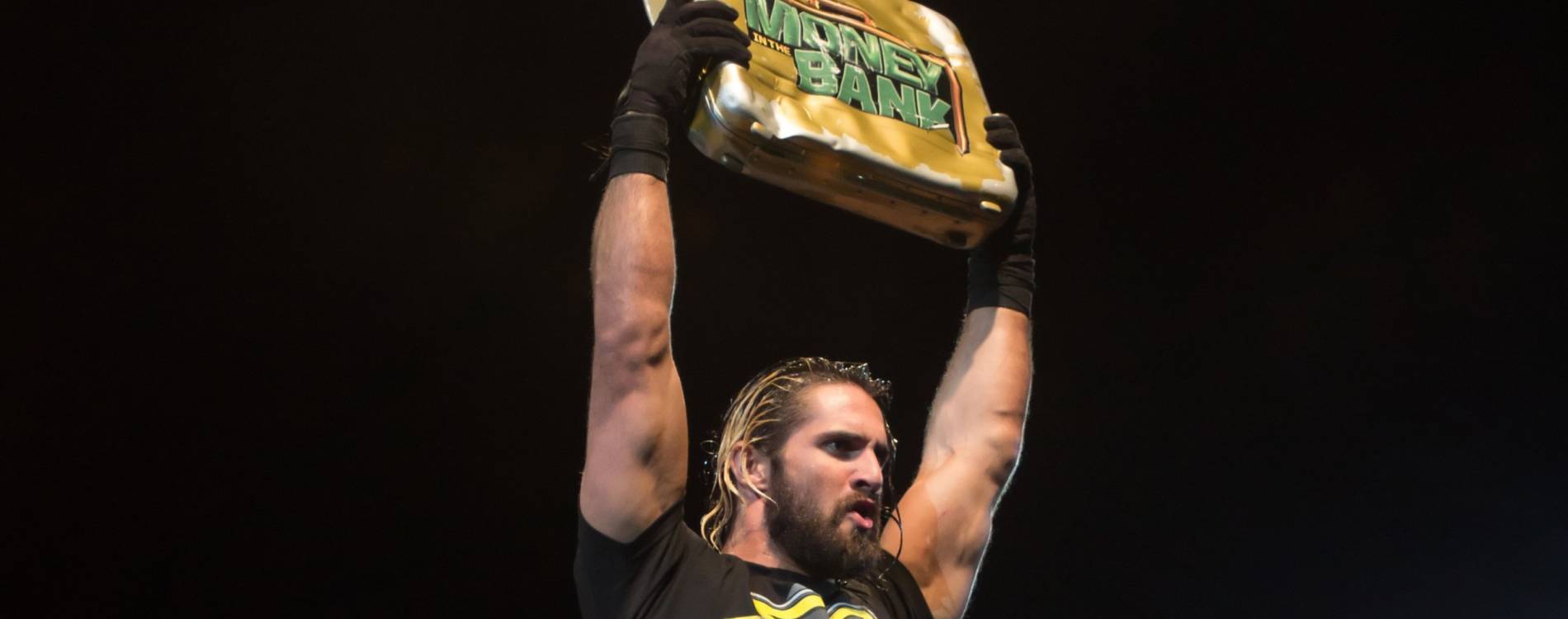 Seth Rollins holds the Money in the Bank briefcase aloft after winning the match in 2015