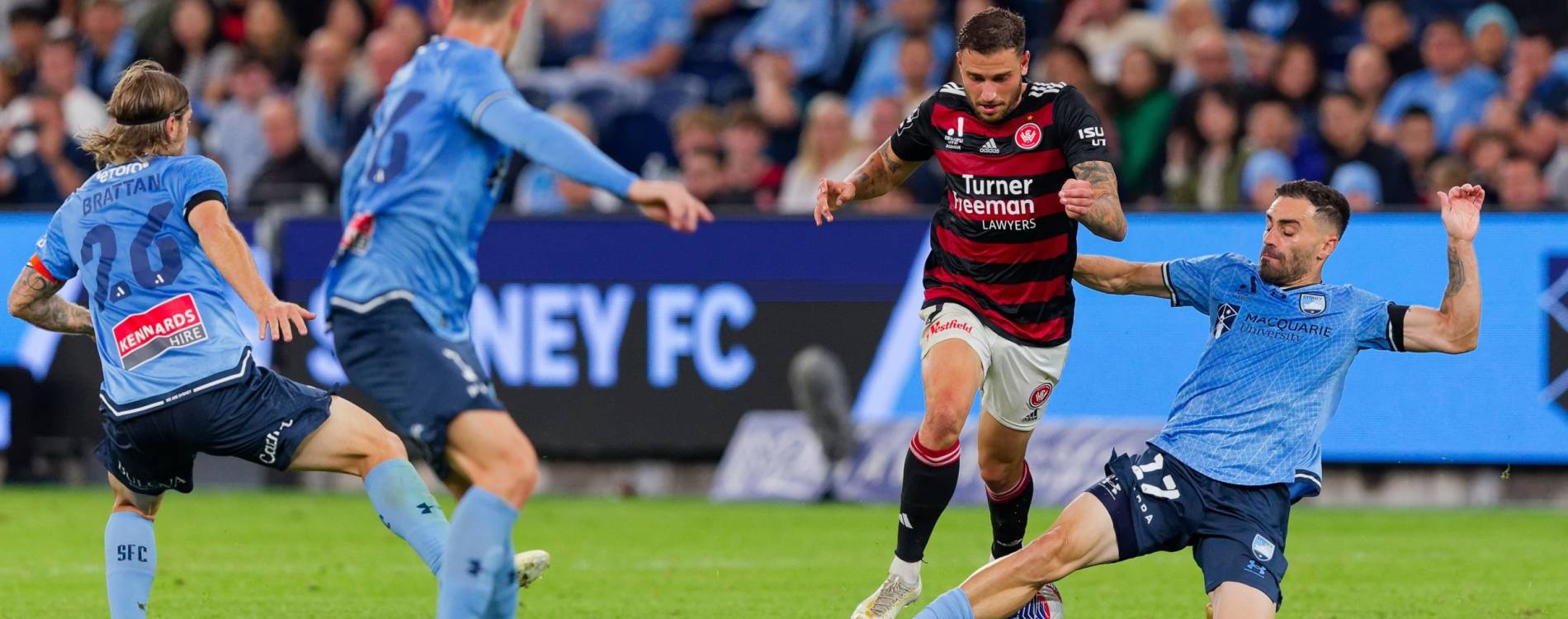 Sydney FC's Anthony Caceres tackles Wanderers' Dylan Pierias